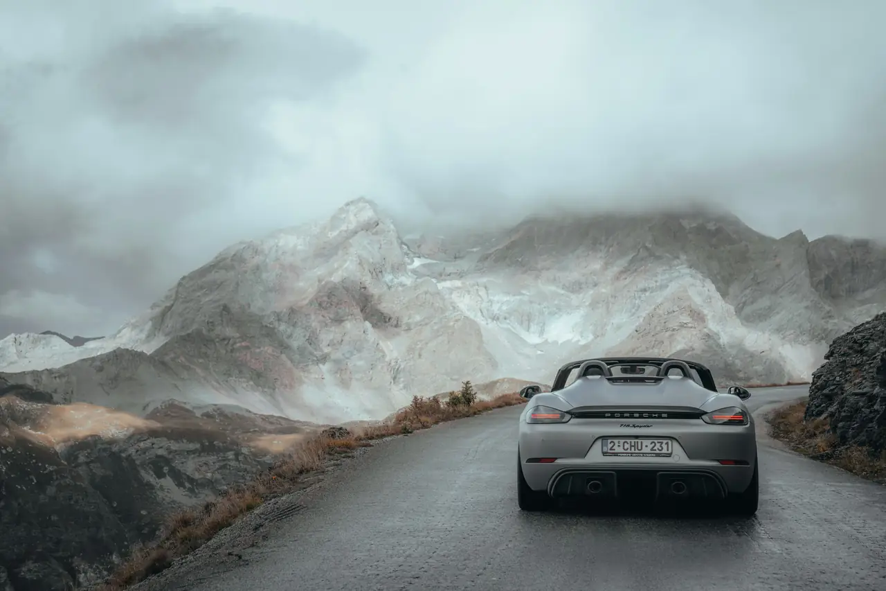 Une Porsche argent sur une route de col, dans la brume